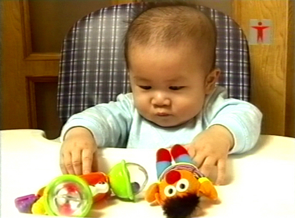 Baby grabbing and playing with toys placed in front of him