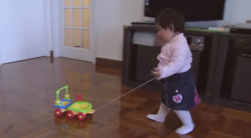 A girl pulling a toy on the floor